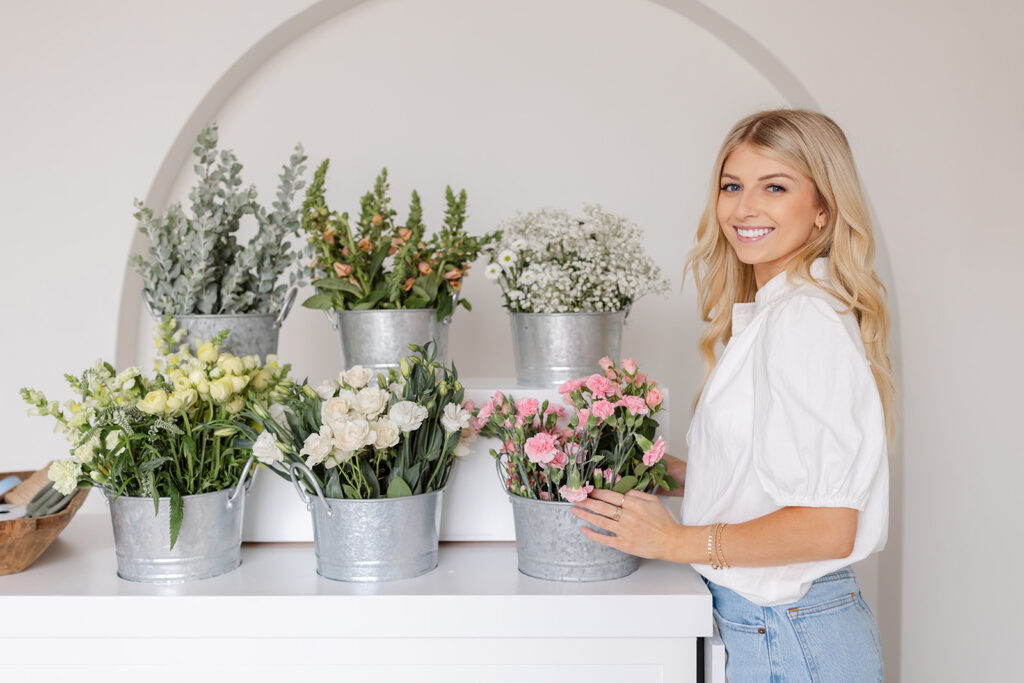 a woman standing next to buckets of flowers