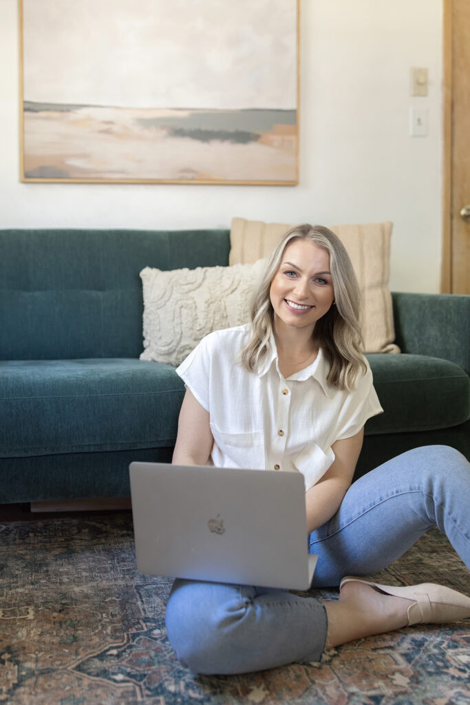 a woman sitting on the floor with a laptop