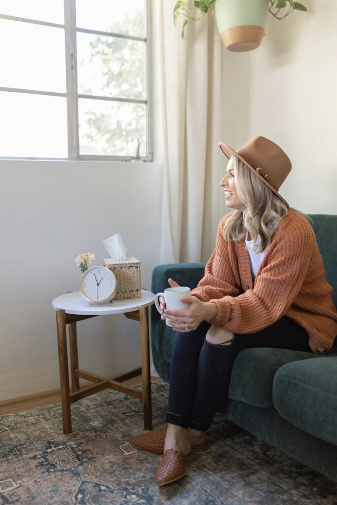 a woman sitting on a couch holding a cup and a coffee cup