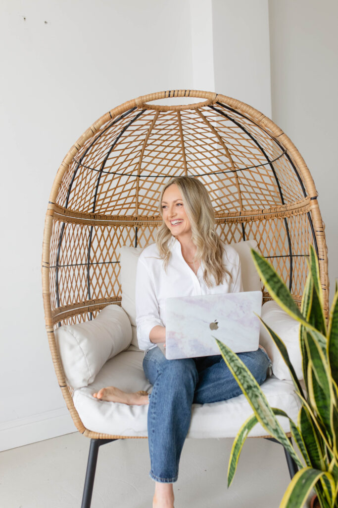 a woman sitting in a wicker chair with a laptop