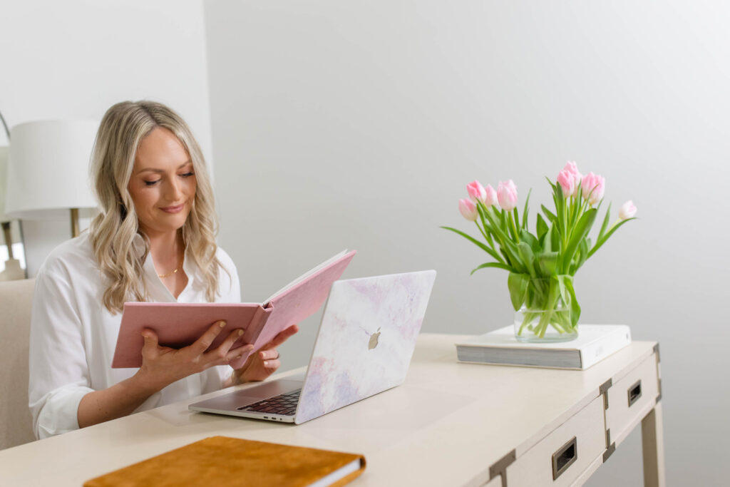a woman sitting at a desk with a laptop and a book