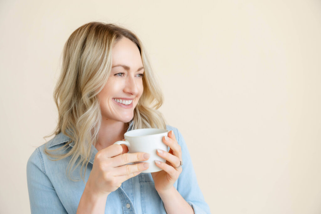 Professional headshot of Sacramento branding photographer Nicole Hodgson smiling with camera.