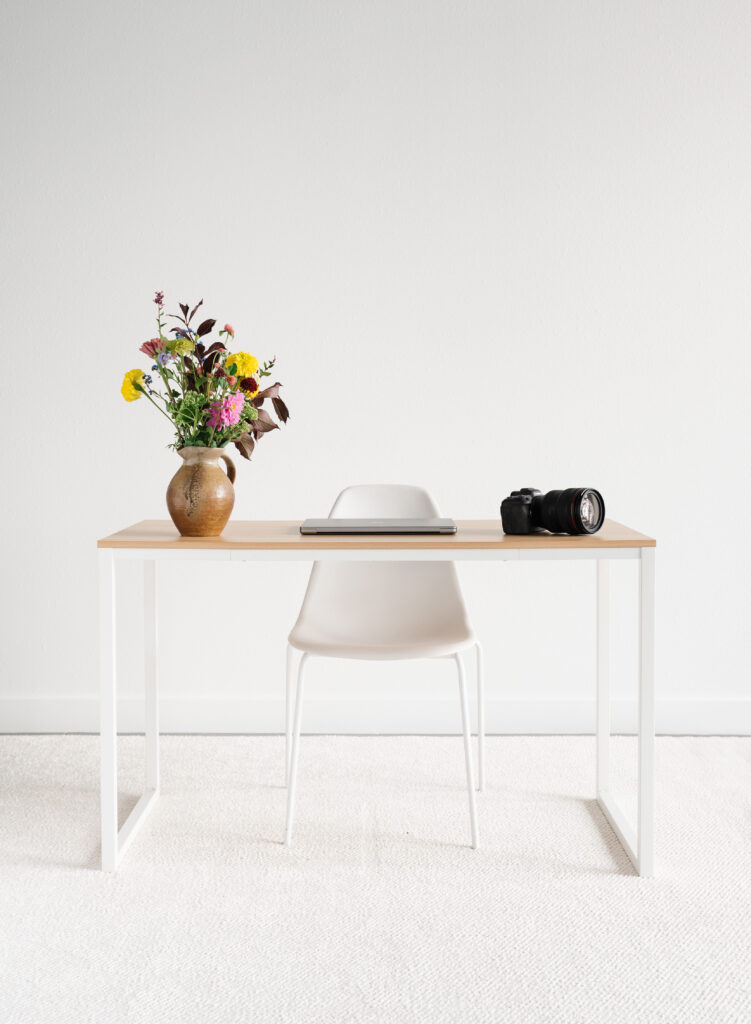 Minimalist desk with flowers and camera