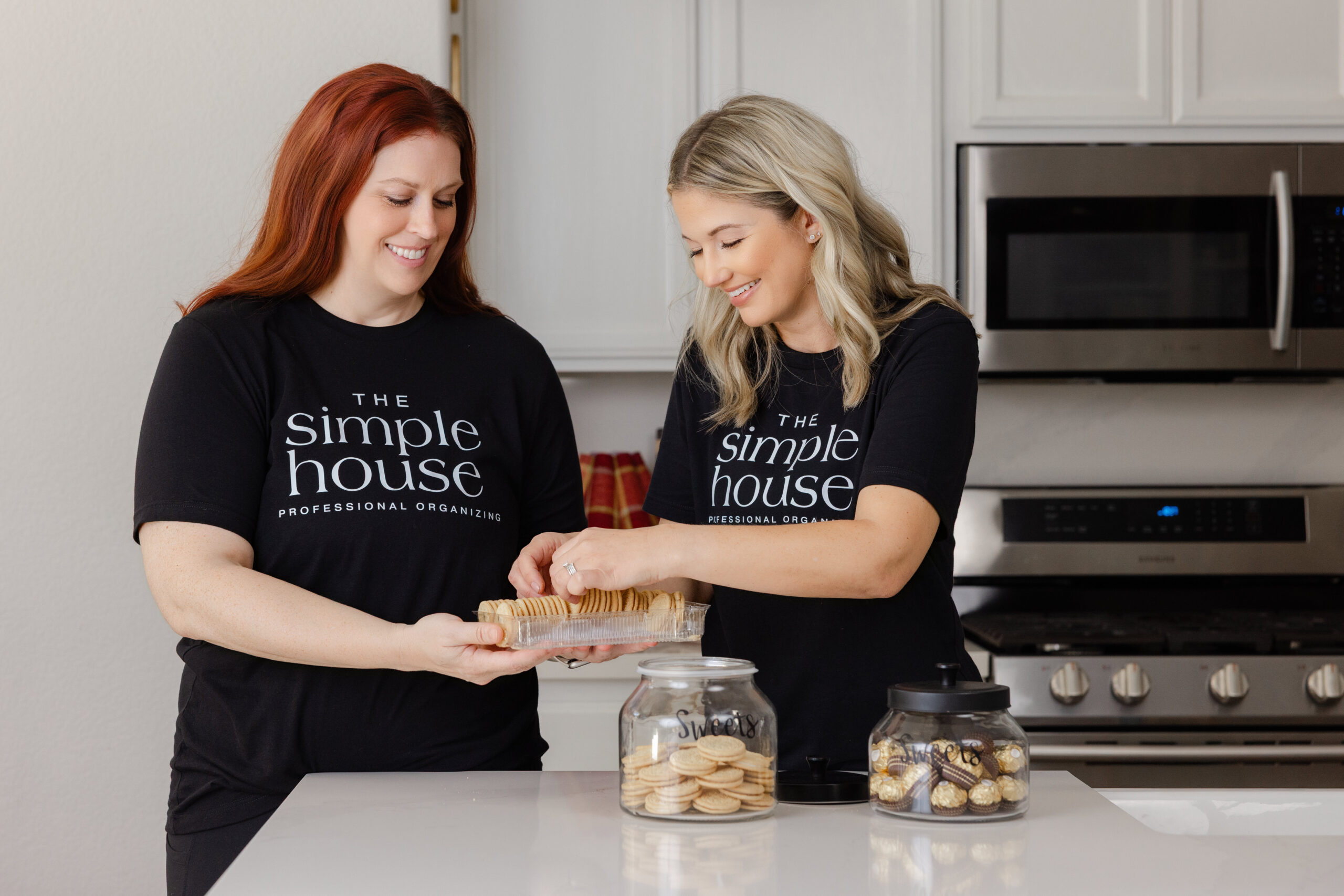 Two women organizing cookies in kitchen.
