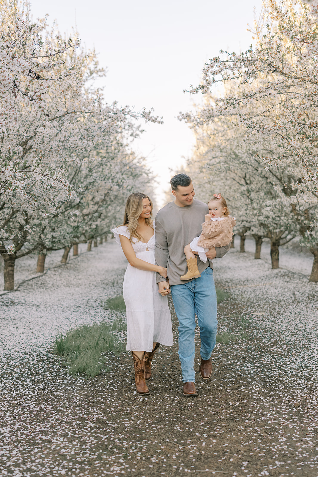 a family of three in an almond blossom orchard in stockton